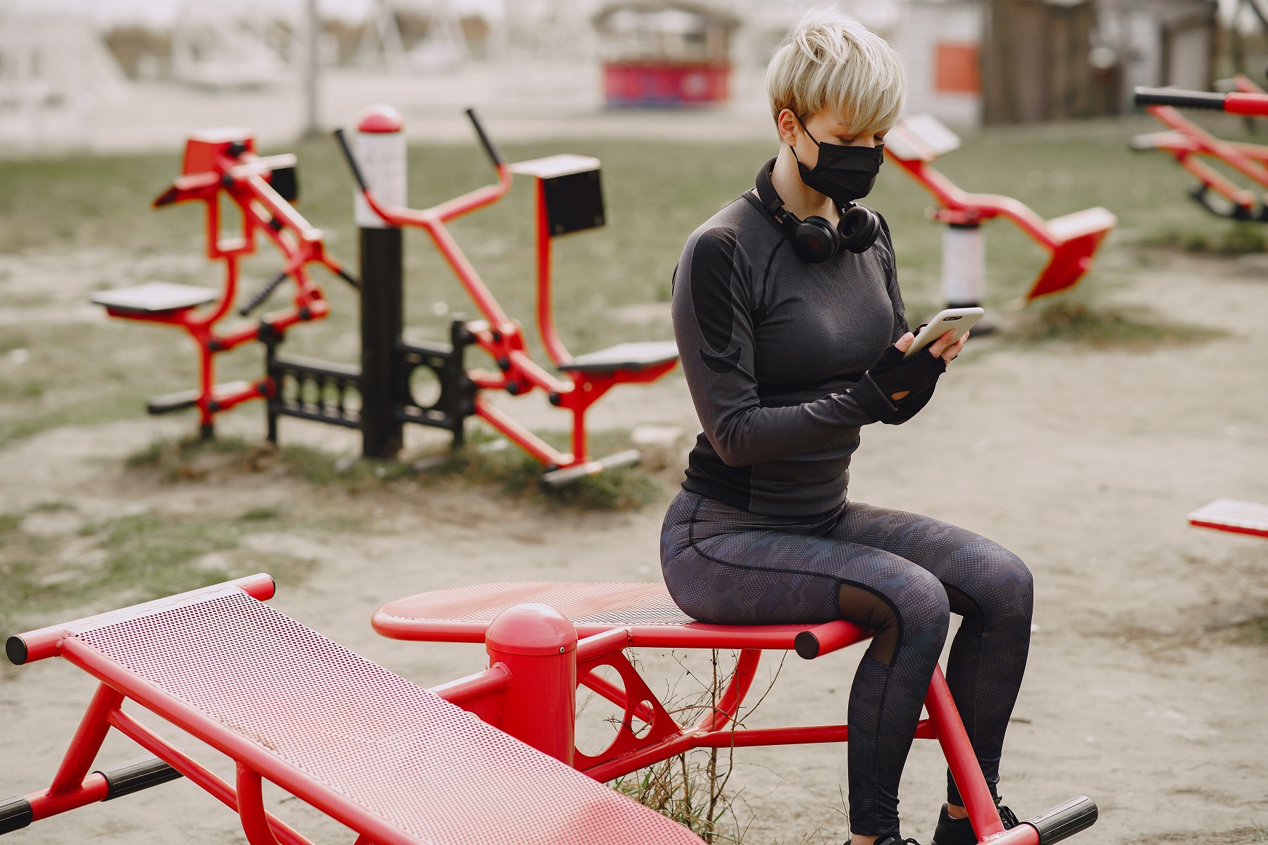 serious young woman in face mask using smartphone sitting on 4127503